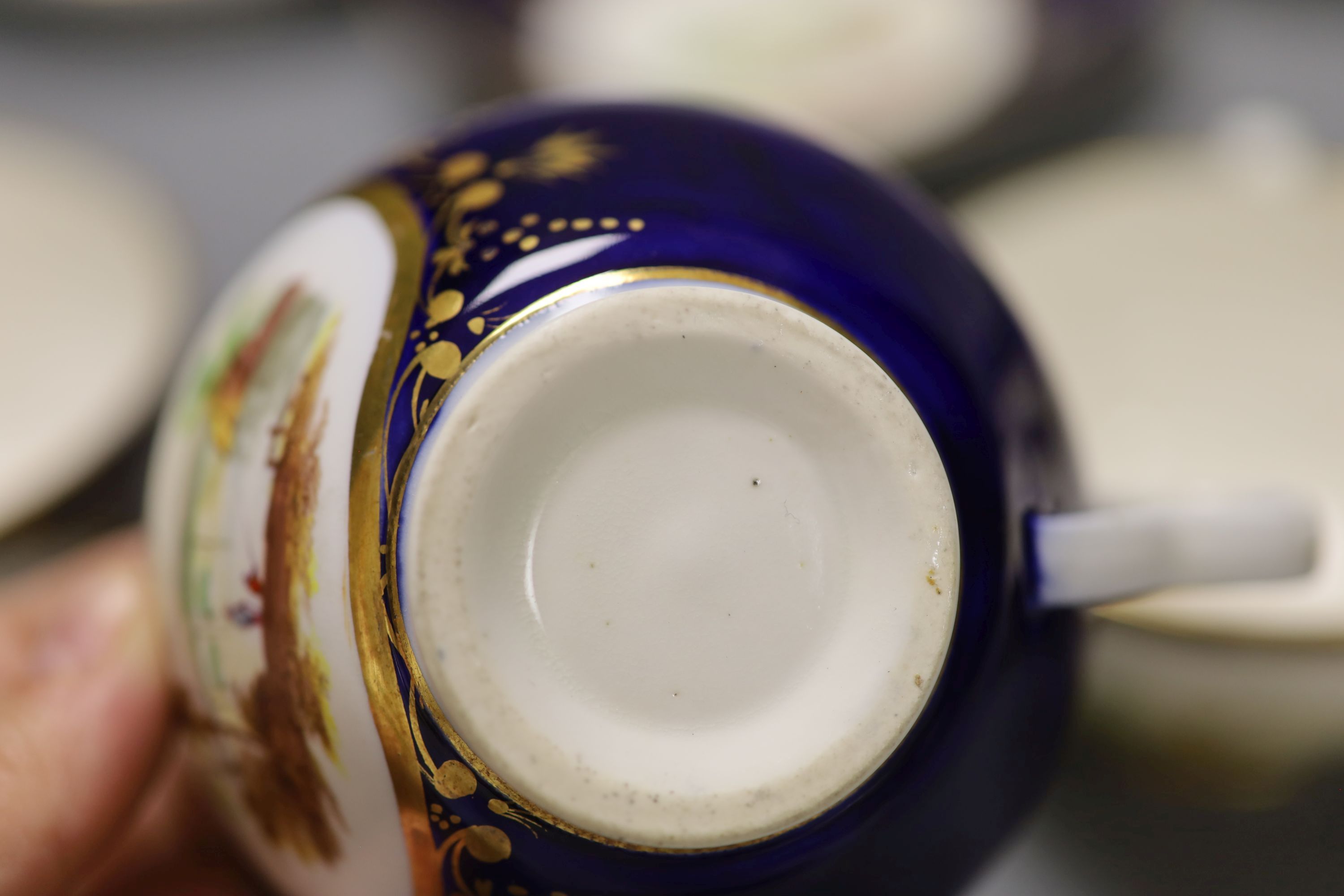 A set of four Derby cups and saucers painted with landscapes on a cobalt blue ground by Henry Lark Pratt, red mark